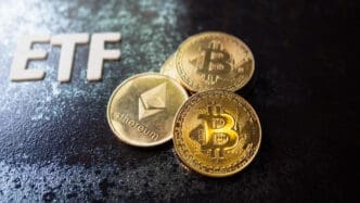 Physical Bitcoin and Ethereum coins next to the letters ETF on a dark surface.