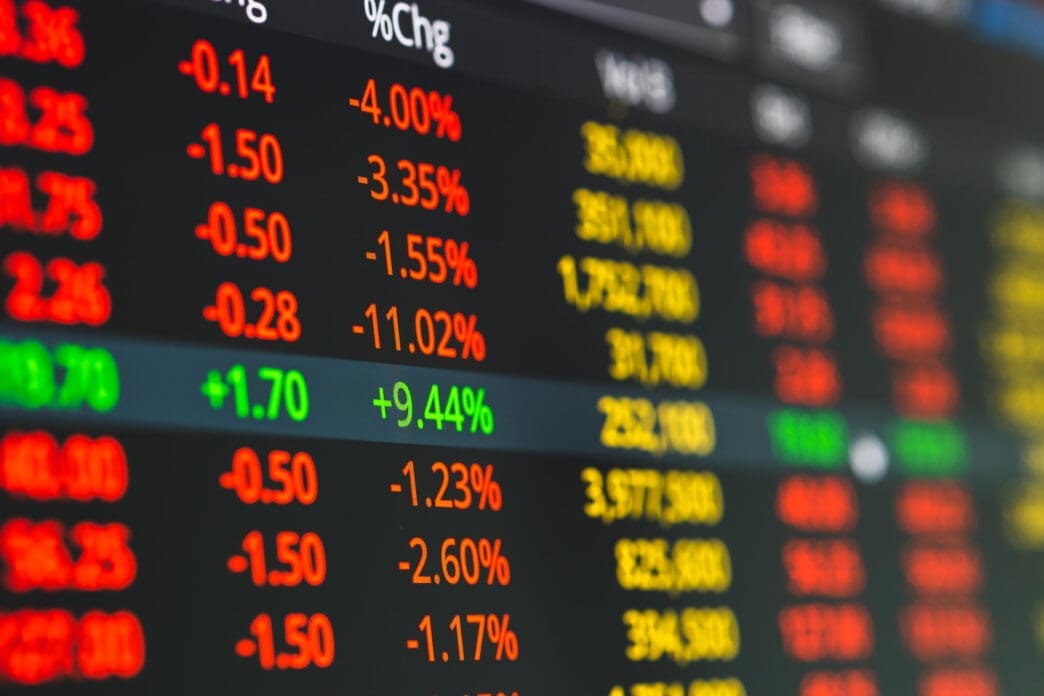 Close-up view of a dark digital stock market screen showing numerous assets with prices and steep negative percentage changes in red and orange.