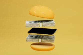 A stylized burger disassembled, with a phone and dollar stacks replacing the typical ingredients.