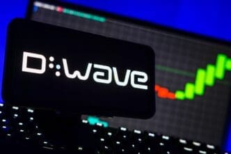 The D-Wave quantum computing logo is displayed on a smartphone, with a rising green stock market chart visible in the background.