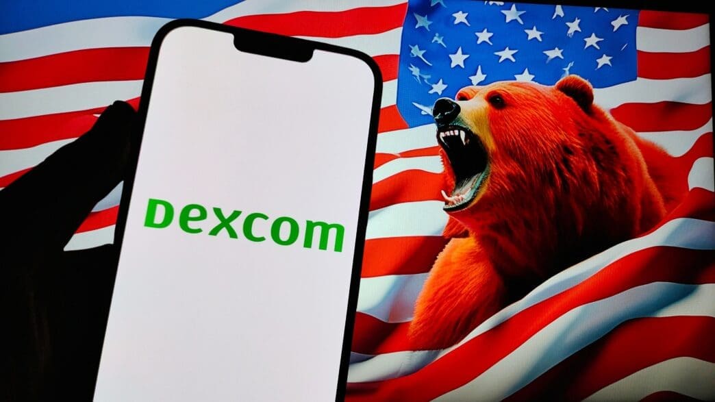 A phone displays the DexCom logo against a backdrop of a snarling red bear and the American flag, symbolizing a stock decline.