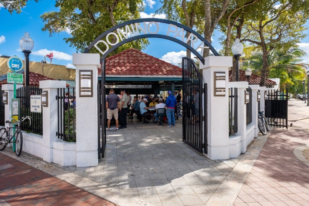 The arched entrance gate to Domino Park in Little Havana, with people playing games inside.