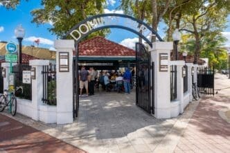 The arched entrance gate to Domino Park in Little Havana, with people playing games inside.