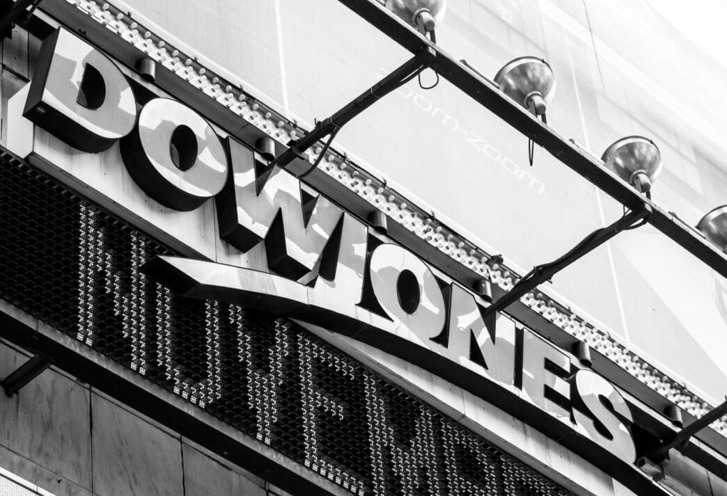 Black and white close-up of the Dow Jones sign and digital ticker in Times Square, NYC.