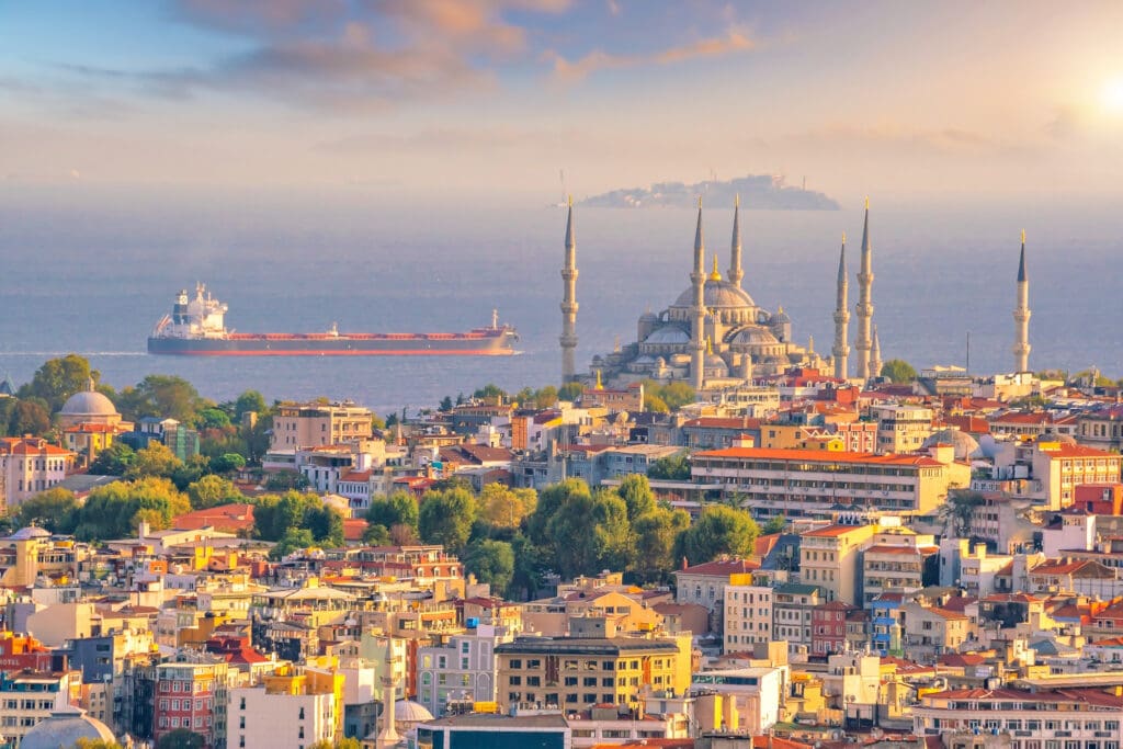 A sunset view of the Istanbul, Turkey cityscape, featuring the Blue Mosque overlooking the Bosphorus Strait.