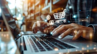 A person's hands type on a laptop, with glowing digital icons for online shopping floating above.