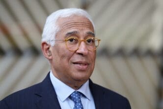 A close-up portrait of EU Council President Antonio Costa wearing glasses and a suit.