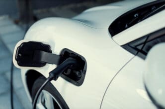 Close-up view of a black charging cable plugged into the charging port of a white electric vehicle.