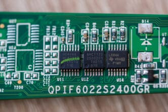 A macro photo of a green circuit board showing Nexperia HC4066, Jabbar AHCT125, and TI LC04A microchips.