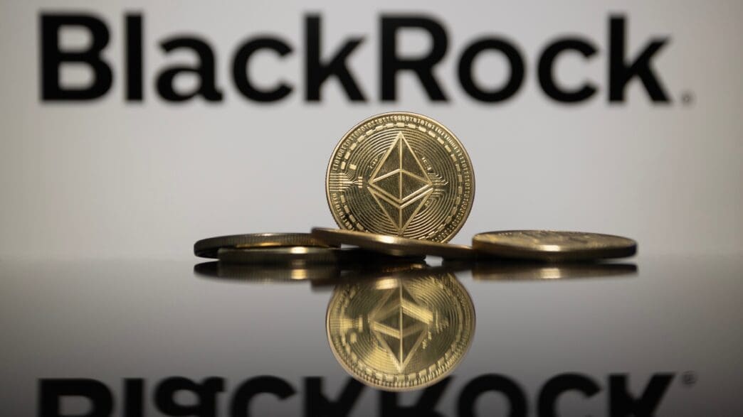 A physical Ethereum (ETH) coin stands reflected in front of the BlackRock logo.