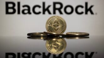 A physical Ethereum (ETH) coin stands reflected in front of the BlackRock logo.