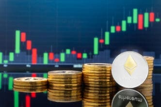 Physical Ethereum coins are stacked in front of a digital screen displaying a green and red candlestick financial chart.