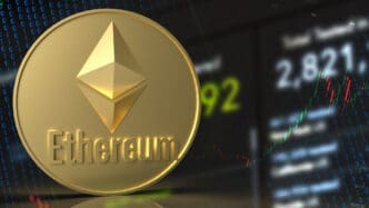 A physical gold Ethereum coin is shown in front of a digital screen with financial data and binary code.