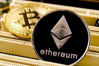 Physical silver Ethereum and gold Bitcoin coins resting on computer hardware.