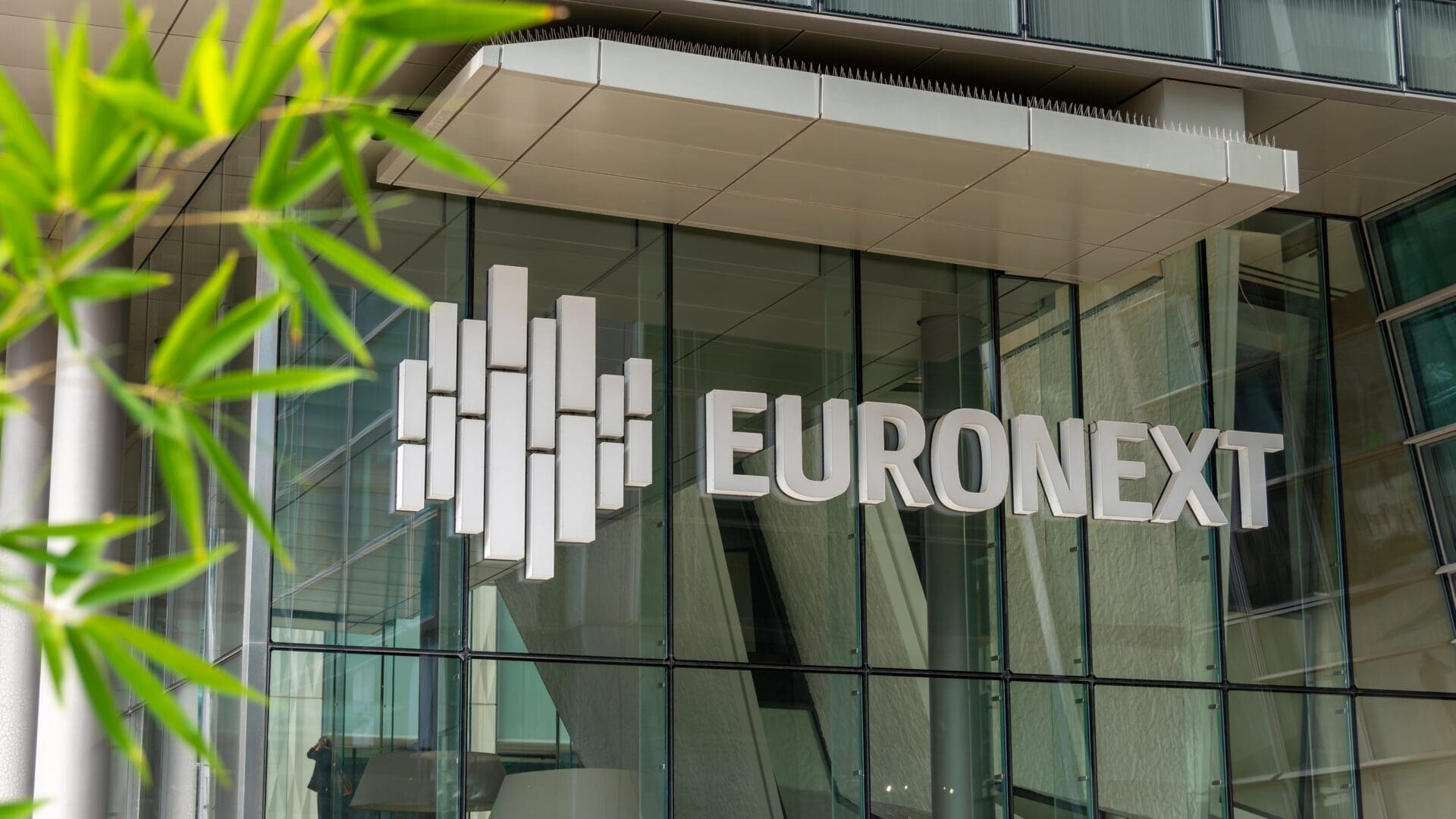The Euronext logo and name are displayed on the glass facade of a modern corporate building in the La Défense business district.