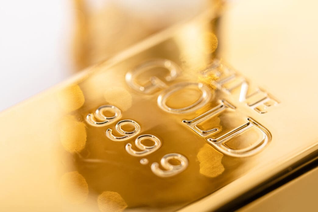 Extreme close-up of a brilliant, reflective gold bullion bar engraved with "FINE GOLD" and "999.9" purity marks