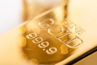 Extreme close-up of a brilliant, reflective gold bullion bar engraved with "FINE GOLD" and "999.9" purity marks
