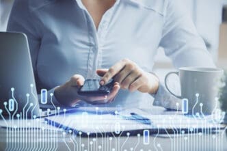 A person in a shirt holds a smartphone at a desk, with a technology graphic overlaid.