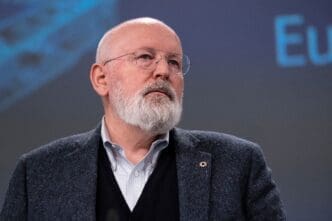 Executive Vice-President Frans Timmermans wearing glasses and a beard, looking up during a press conference.