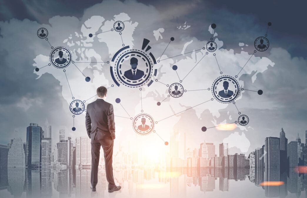 Man in suit looks at a global network of people icons superimposed on a cityscape