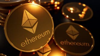 Close-up of multiple physical-looking gold coins featuring the Ethereum logo and name, illuminated in a dramatic, dark setting.