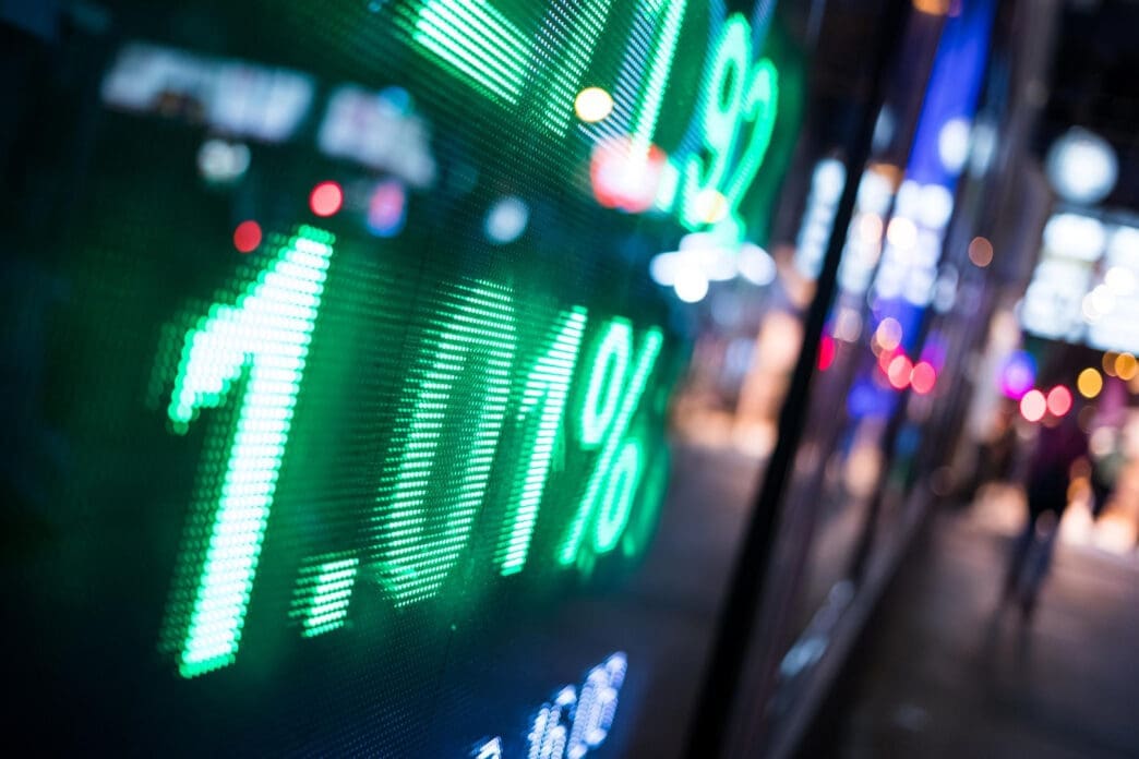 Close-up of a green LED stock market ticker showing a price increase.