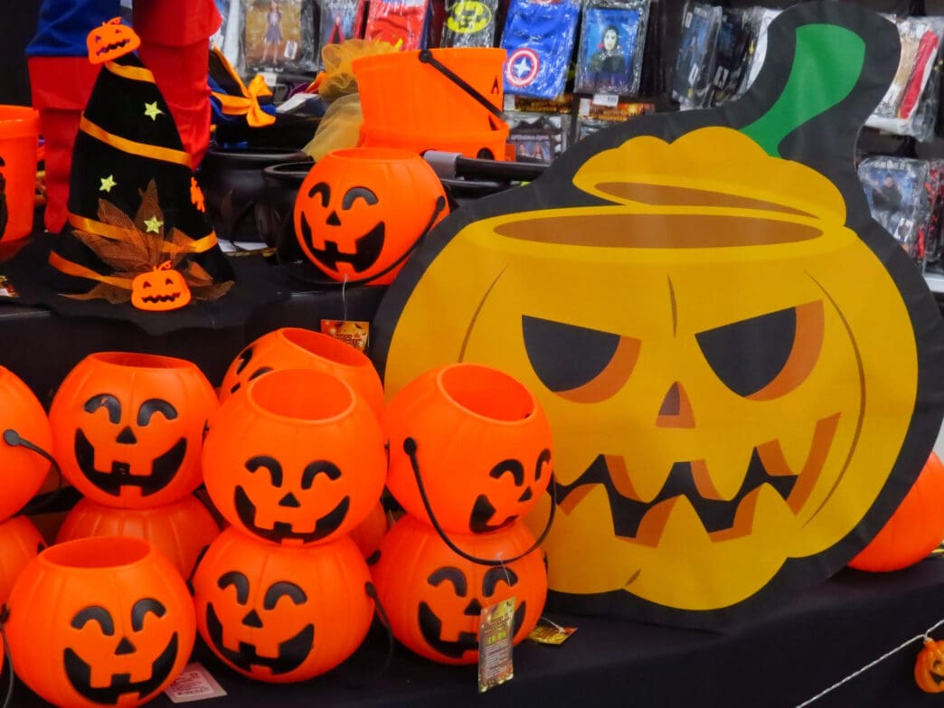 A display of Halloween-themed decorations, including pumpkin buckets, a witch hat, and a large cardboard pumpkin cutout