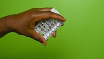 Hand of an African American female holding a blister pack of birth control pills.
