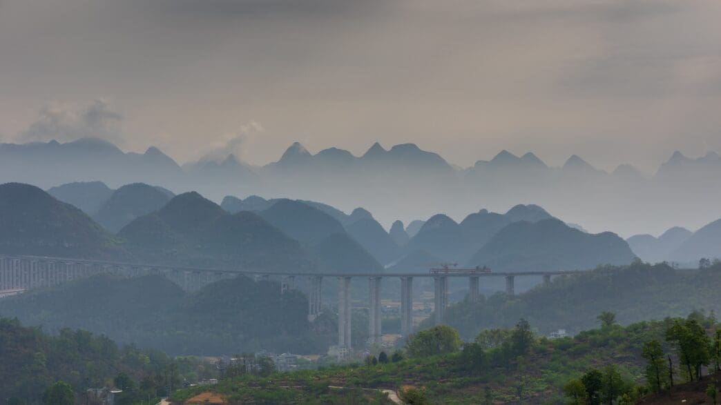 Elevated highway bridge spanning a mountainous canyon in hazy weather
