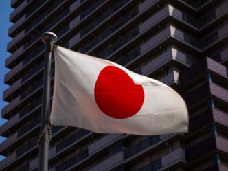Japanese flag waves in front of a modern building.