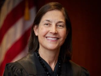 Judge Karin Immergut smiles in a judicial robe with a pearl earring