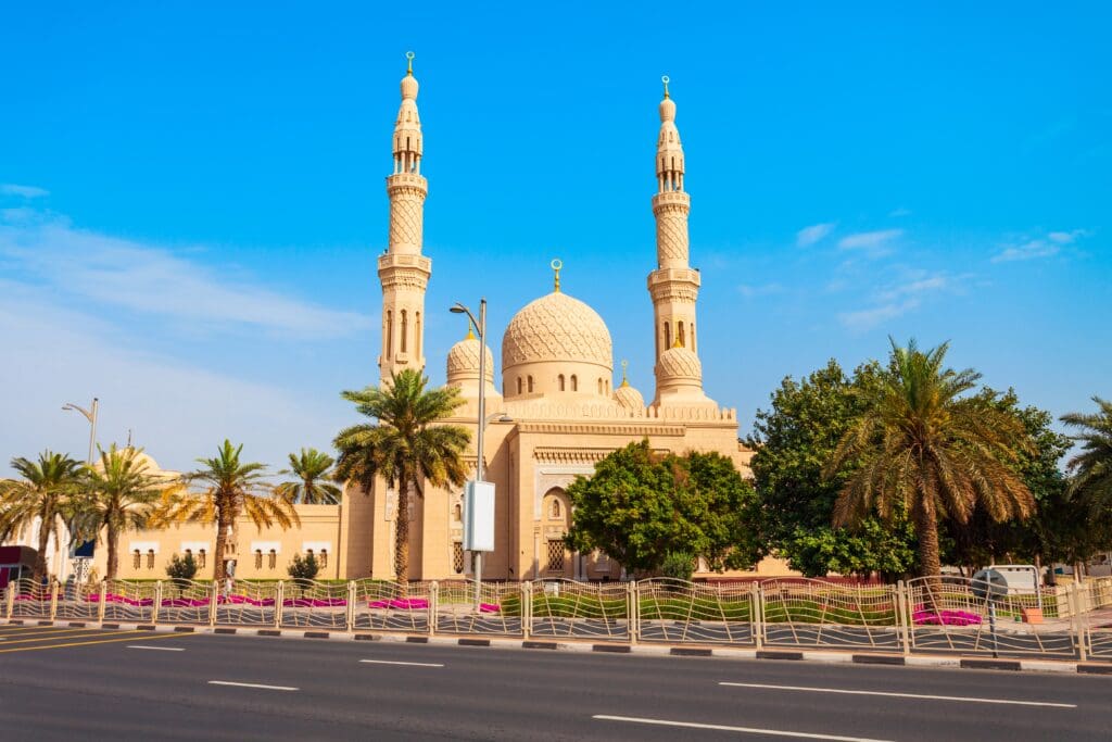 The beige Jumeirah Mosque with two tall minarets, set against a clear blue sky in Dubai.