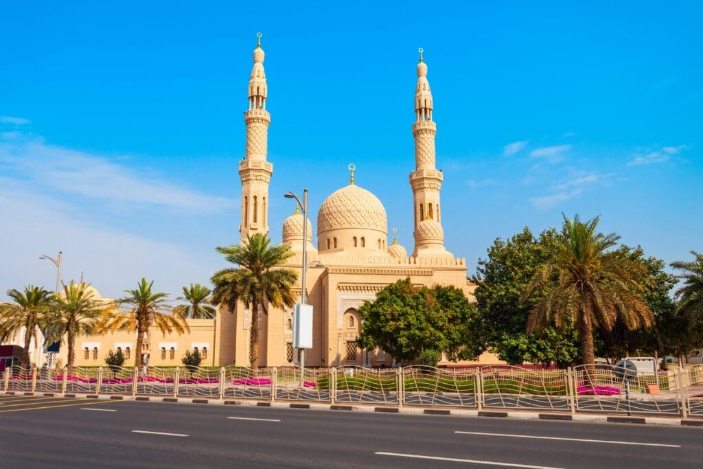 The beige Jumeirah Mosque with two tall minarets, set against a clear blue sky in Dubai.