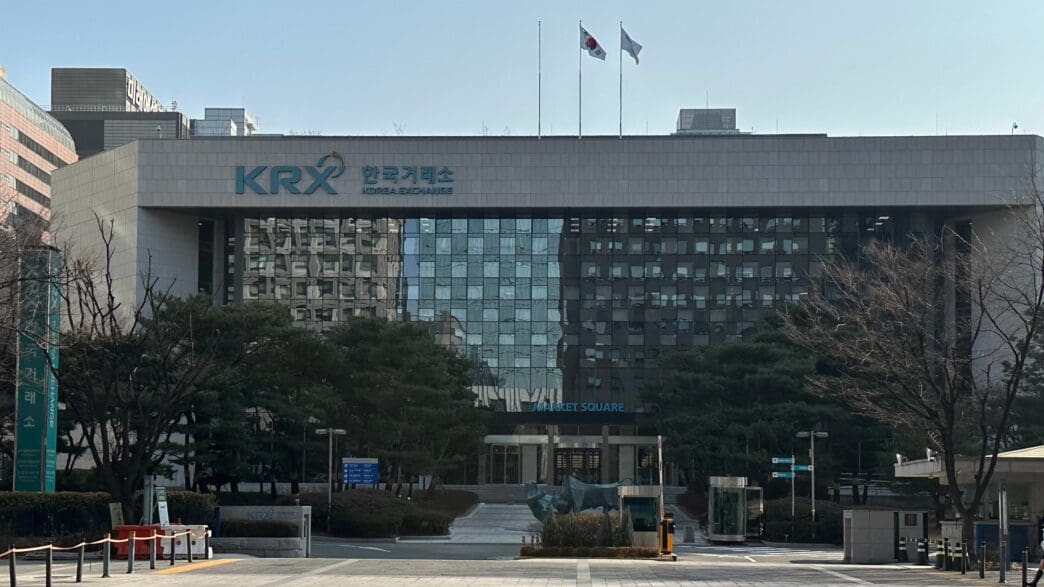 Exterior view of the KRX Korea Exchange building in Seoul with Korean flags flying above.