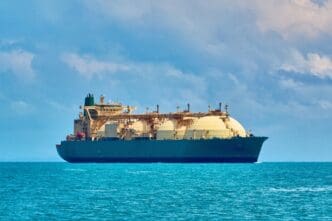 An LNG tanker sails on the ocean under a cloudy blue sky