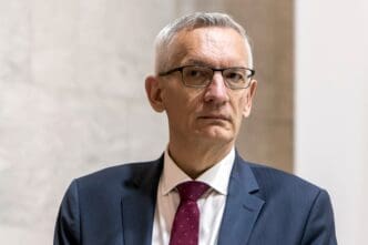 Close-up portrait of Martin Jager, president of Germany's BND intelligence service, wearing glasses, a navy suit, and a red tie.