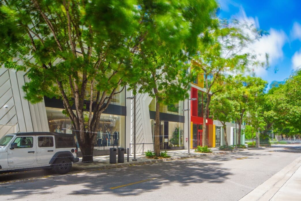 A long exposure photo of a modern street in the Miami Design District with trees and storefronts.