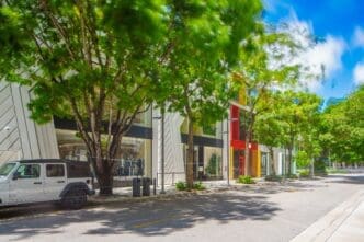 A long exposure photo of a modern street in the Miami Design District with trees and storefronts.