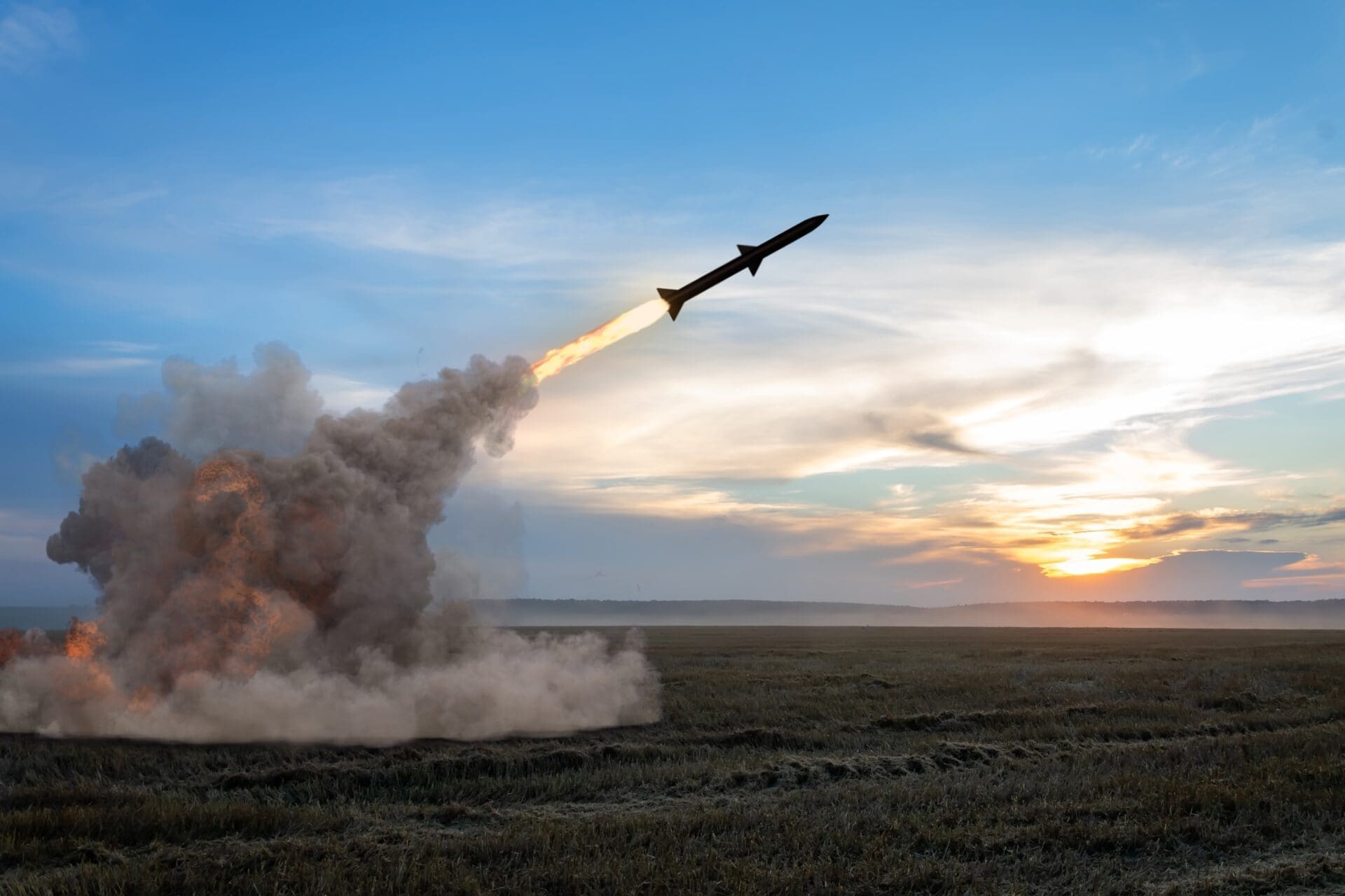 A missile is launched from a field, leaving a trail of fire and smoke.