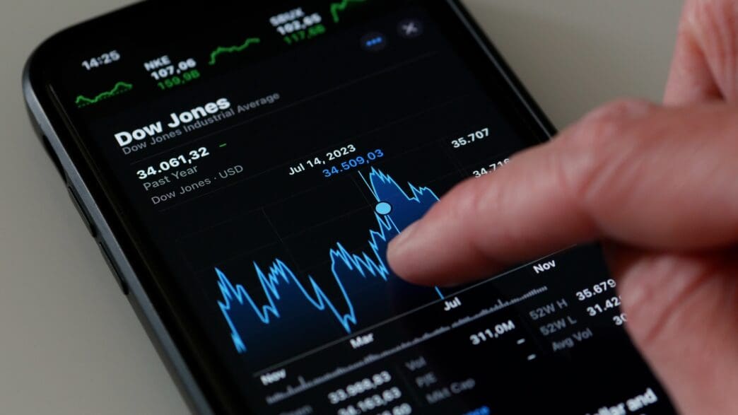 A finger touches the Dow Jones Industrial Average chart on an iPhone stock app.
