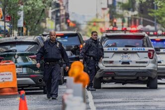 NYPD officers in uniform and police vehicles on a city street, suggesting an active scene