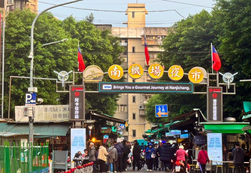 A large yellow sign marks the crowded entrance to the Nanjichang Night Market in Taipei.