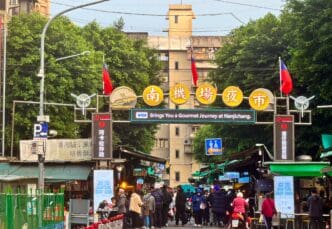 A large yellow sign marks the crowded entrance to the Nanjichang Night Market in Taipei.