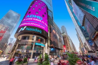 A low-angle shot of the Nasdaq building and other skyscrapers in Times Square, New York.