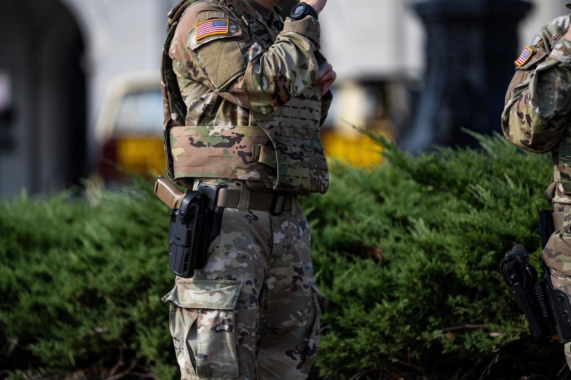 Soldier in camouflage uniform and tactical vest with a handgun in a holster