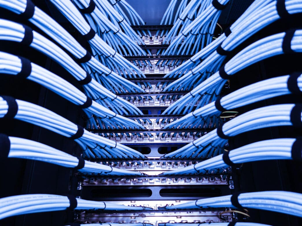 Neatly organized blue network cables plugged into servers in a data center rack.