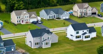 Aerial view of large, modern, single-family homes with green lawns in a suburban development.