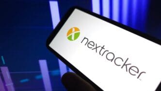 A smartphone displays the Nextracker Inc logo, with a financial chart in the background.