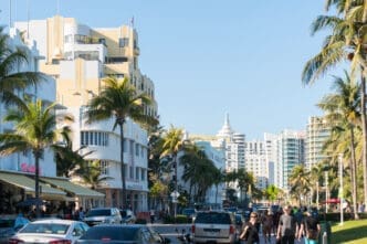 People walking along Ocean Drive in Miami Beach, lined with Art Deco hotels and palm trees.