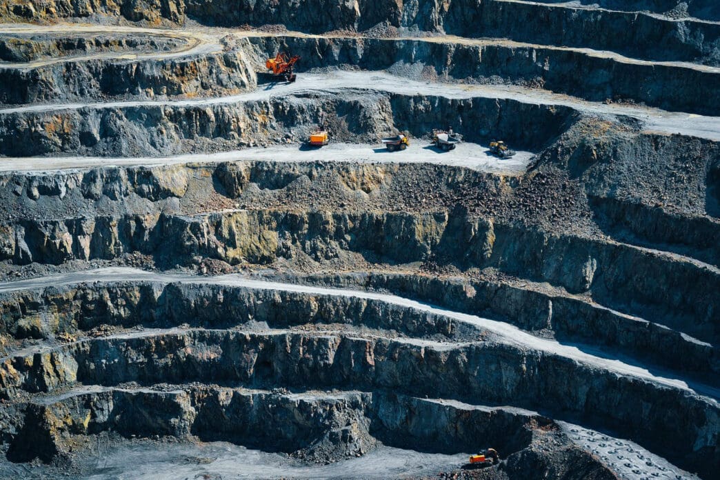 Large open-pit mine with heavy machinery on multiple levels